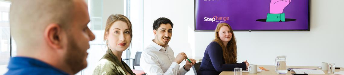 man and two women smiling in a meeting at work